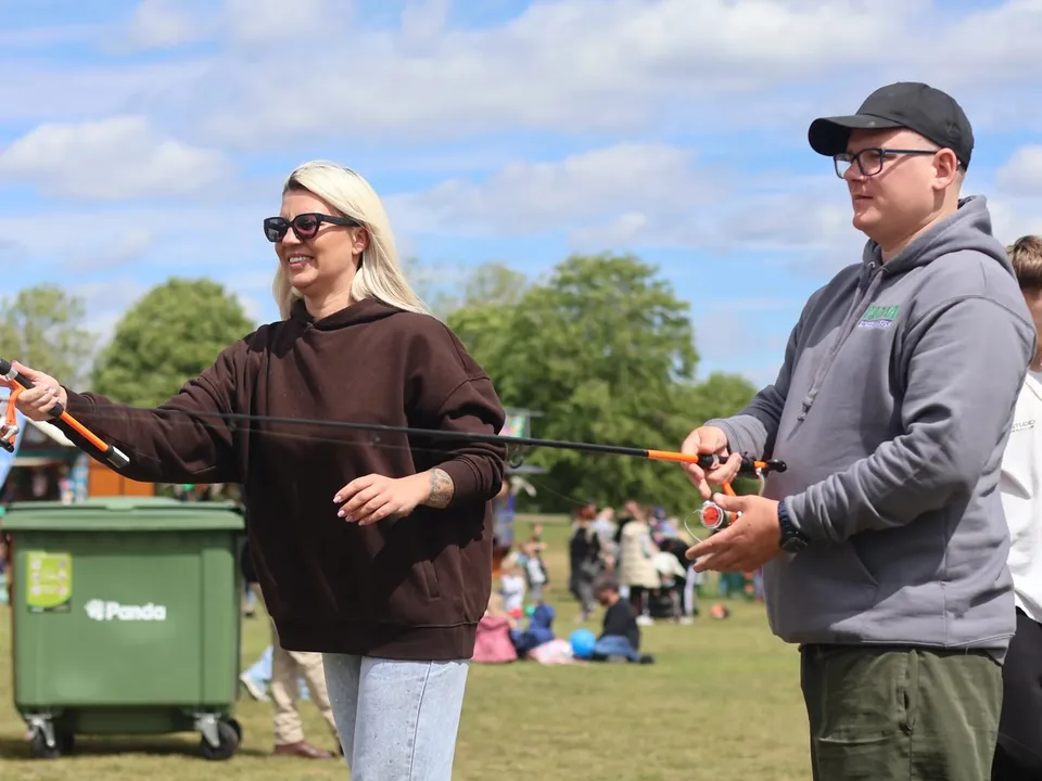 An adult learning to cast with a coach at a club event