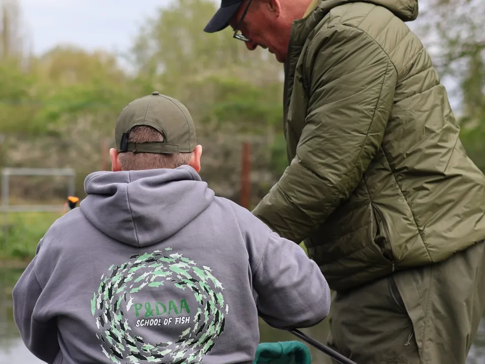 A coach working one to one with a junior angler on the bank