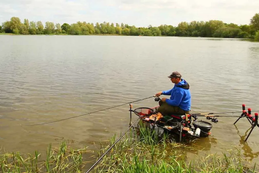 A match angler fishing from a platform on a lake at Ferry Meadows