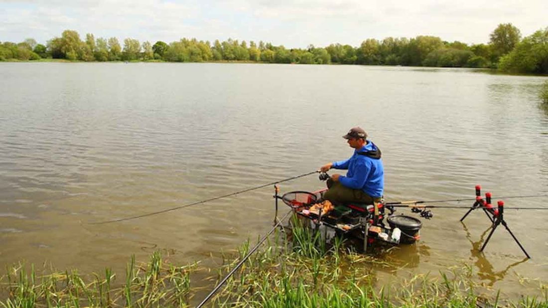 An angler fishing the pole from a platform at Ferry Meadows