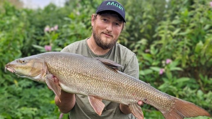 Robbie Cunnington holding a 12lb 14oz barbel at Elton Fishery.